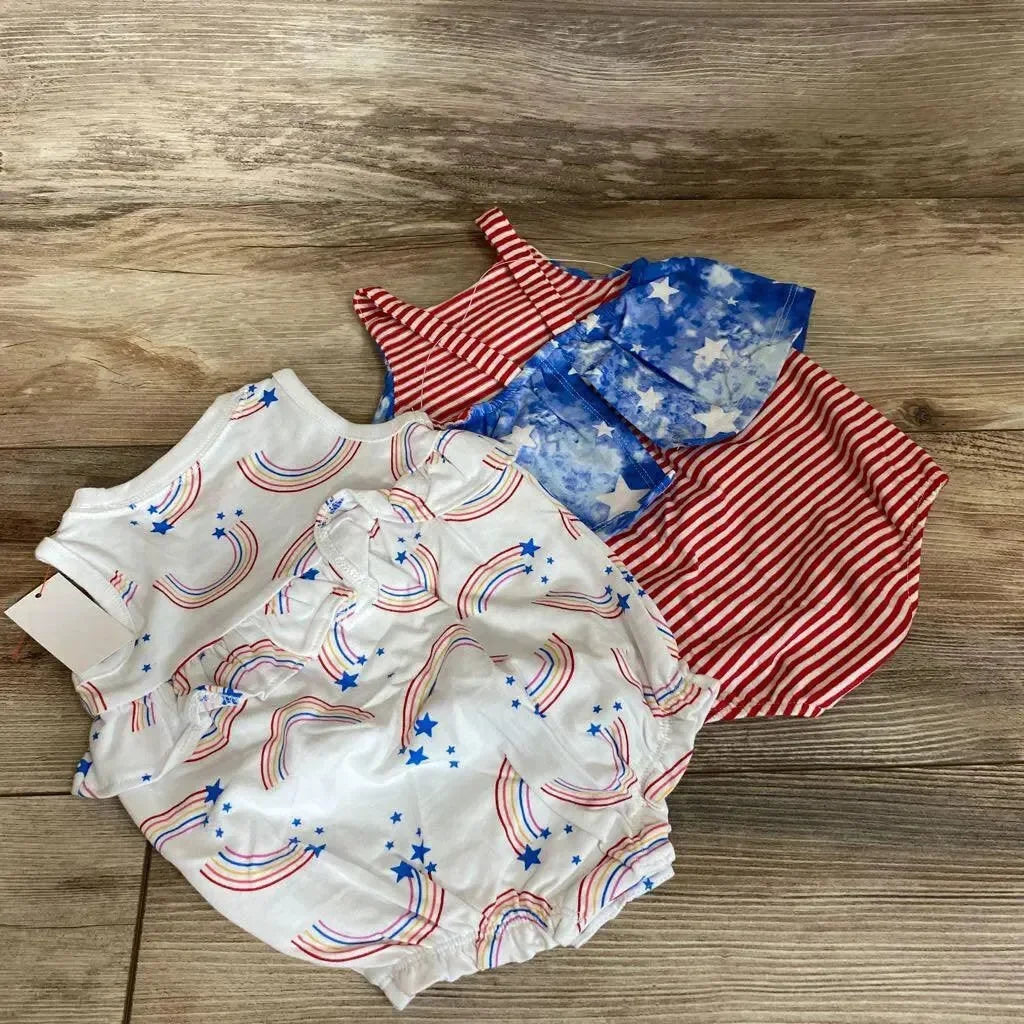 Flat lay of two baby rompers: white rainbow-print with blue stars; red-and-white striped with blue star bib on wood floor
