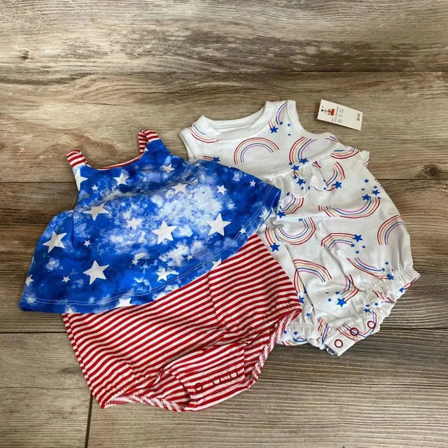 Flat lay of 2 baby rompers: white rainbow-print romper and red-striped romper with blue star top on wood floor