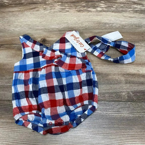 Top down view of Cat and Jack plaid baby romper with ruffle collar, snapped bottom and headband on wood background