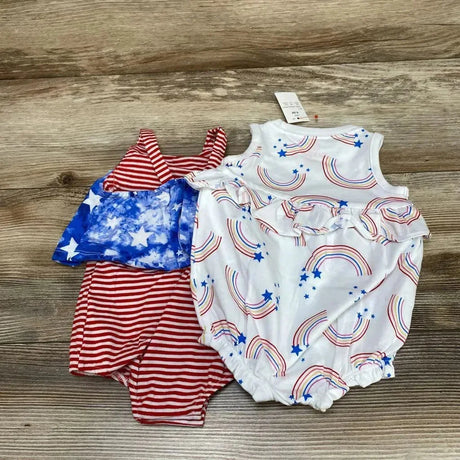 Flat lay of two Cat and Jack baby rompers showcasing a white rainbow-print ruffle romper and a red-and-white striped romper on wood background