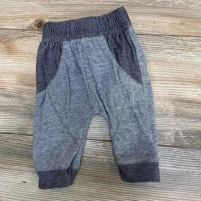 Front view of Cat & Jack newborn pants showcasing elastic waistband, front pockets, and ribbed cuffs on a light wood background