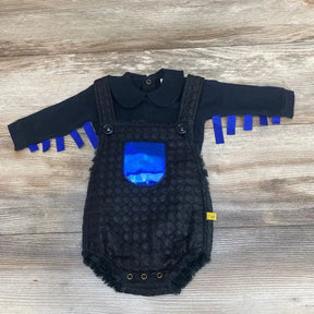 Flat lay of Chua bodysuit and faux-fur romper showcasing quilted texture, shiny blue front pocket and blue ribbon sleeve fringe on light wood background