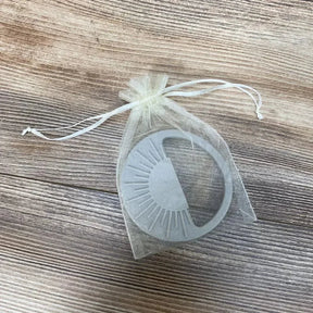 Top-down view of Avery & Everett grey silicone teether with textured ridges in a sheer organza pouch on wood surface