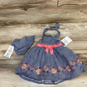 Flat lay of navy gingham baby dress and matching bloomers 3-6M showing pink ribbon waist and floral embroidery on wood floor