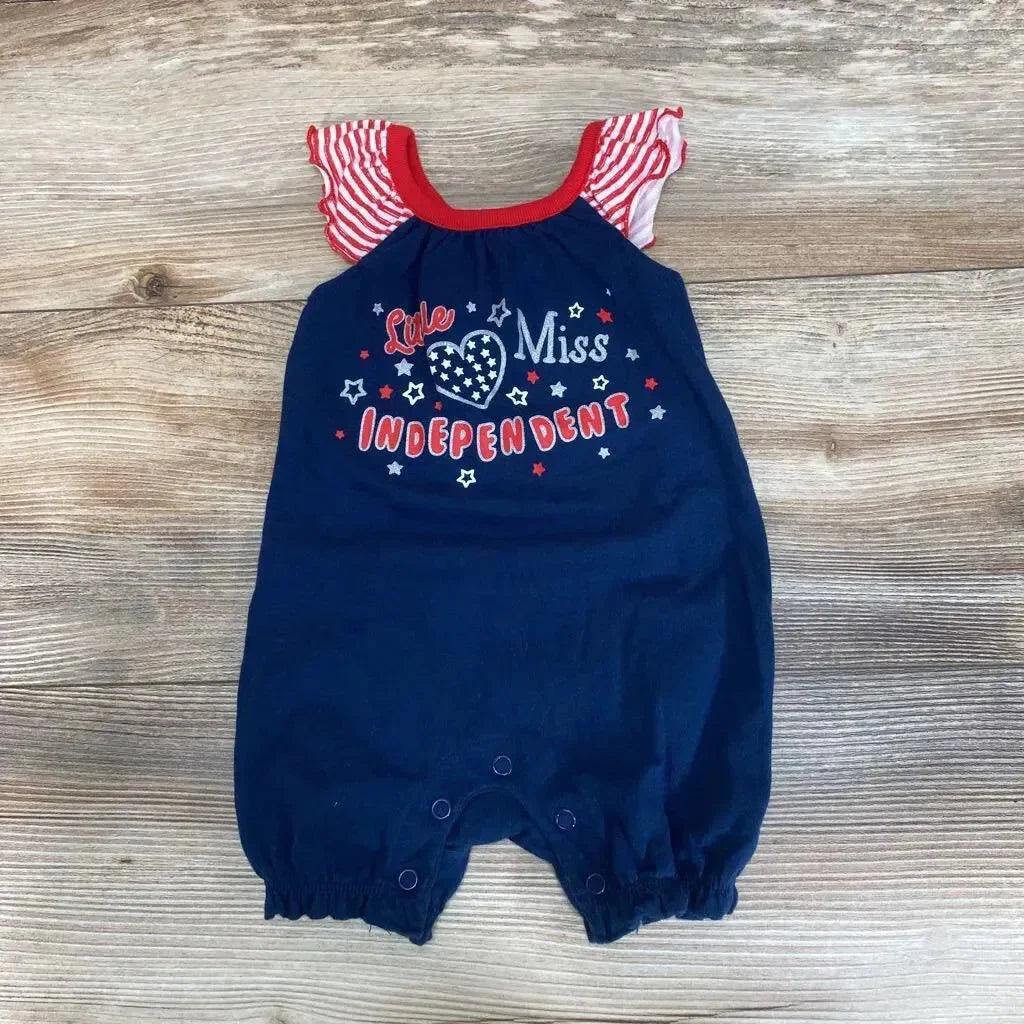 Flat-lay of navy baby romper showing 'Little Miss Independent' graphic, striped ruffle sleeves, and snap crotch on wood background