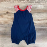 Flat lay of navy baby romper (0-3 months) showcasing red-and-white striped ruffle sleeves and elasticized leg openings on wood background