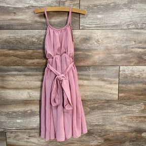 Front view of Bailey's Blossoms pink sleeveless baby dress (9-12 months) showcasing tied waist sash and spaghetti straps on wood-plank background