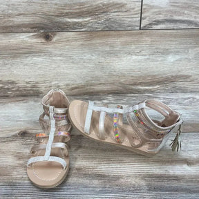 Angled view of Angel gladiator sandals showing holographic straps, glitter T-strap and back zipper on wood background