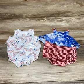 Flat lay of two newborn Cat & Jack rompers: white rainbow-and-star romper and red-striped romper with blue star top on wood