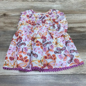 Flat lay of pink smocked baby dress (6-12m) showing butterfly all-over print, long sleeves and purple pom-pom trim on wood background