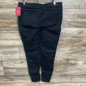 Back view of black Isabel maternity utility jeggings showing back pockets, tapered ankles and pink brand tag on wood floor