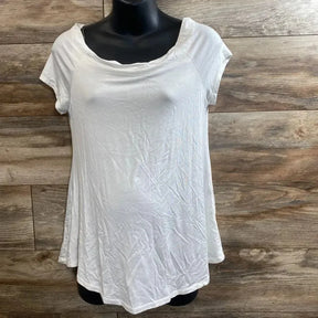 Front view of white maternity short-sleeve tunic showing flared hem and scoop neckline on black mannequin against wood background