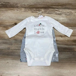 Flat lay of white long-sleeve baby bodysuit reading snow much love, gray snowman-print bodysuit underneath on wood background