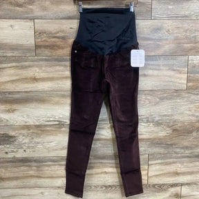 Front view of burgundy Isabel maternity skinny jeans size 00 showing crossover belly panel, hanging on wood plank background