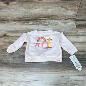 Front flat-lay of pink Cat & Jack baby sweatshirt (3-6M) showcasing rainbow and cloud graphic and ruffled shoulder detail on wood floor background