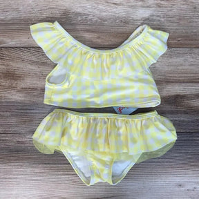 Flat-lay of size 4T toddler yellow gingham 2-piece bikini with ruffle neckline and skirted bottoms on wood background