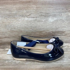 Side view of pair of navy patent bow ballet flats size 9C showing patent finish and toe bows on wood-grain surface