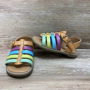 Three quarter view of Cat and Jack toddler sandals showcasing pastel rainbow straps and tan ankle buckle on wood background