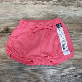 Top-down view of pink Okie Dokie bubble shorts showing elastic waist with bow and gathered hem, 3M tag on wood background