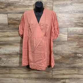 Front view of coral maternity wrap top on mannequin with V neck, puff sleeves and empire waist against wood plank background