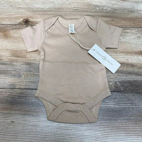Flat-lay of Clay Colored Organics newborn short-sleeve bodysuit showing front with three crotch snaps and hang tag on wood background