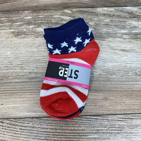 Top-down view of toddler ankle socks (size 2–3) showcasing navy cuff with white stars and red-and-white stripes, wrapped with a gray 'STEP up' label on wooden background