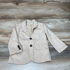 Front flat lay of tan toddler blazer (Cat & Jack, size 2T) showing two black buttons, flap pockets, and notch lapel on wood background
