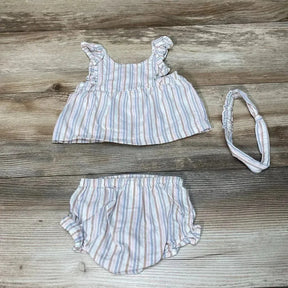 Flat lay of baby three-piece striped top, bloomers, and matching headband showing pastel vertical stripes and ruffle shoulder straps on wood floor